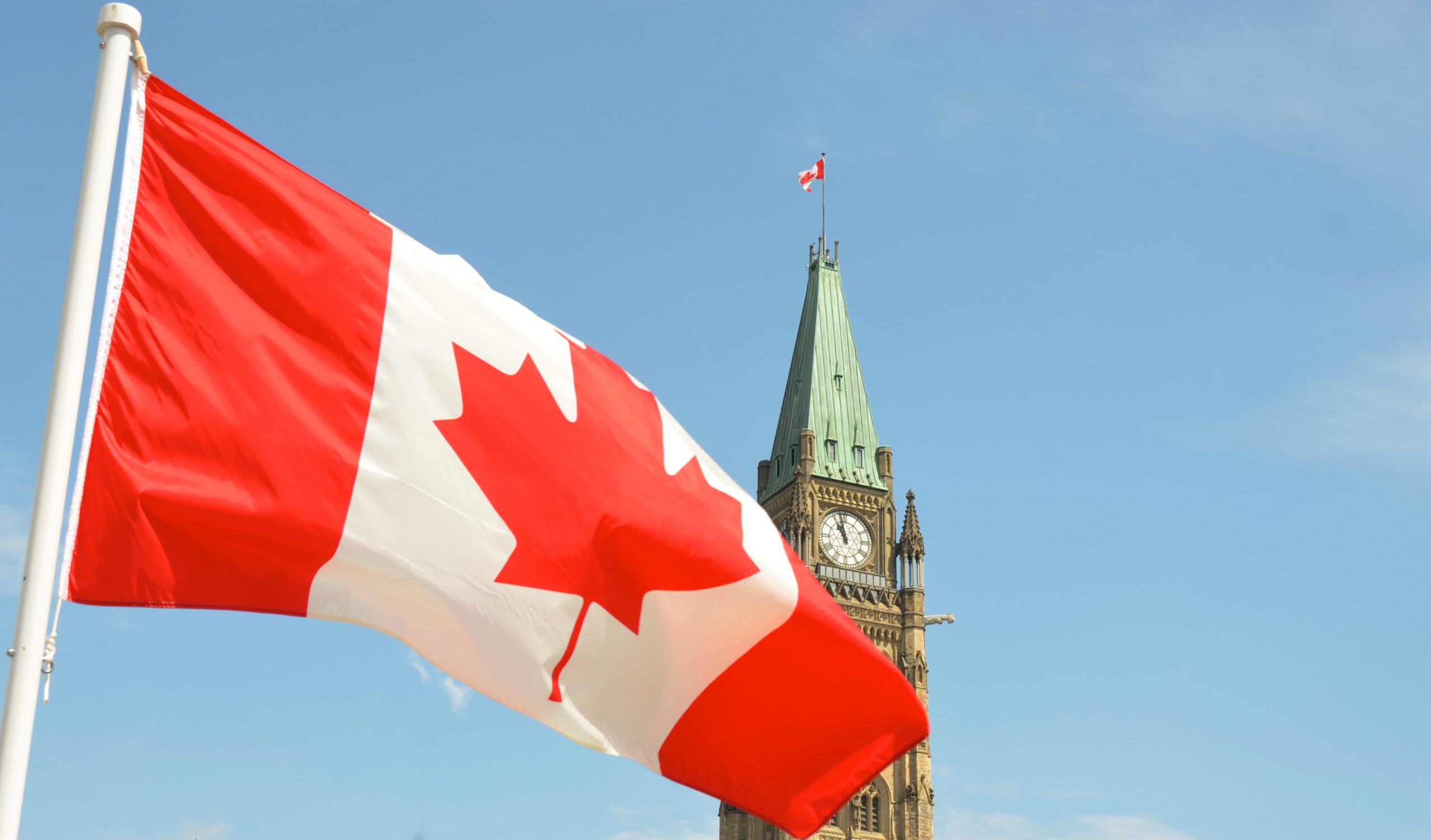 canadian flag with parliament in background